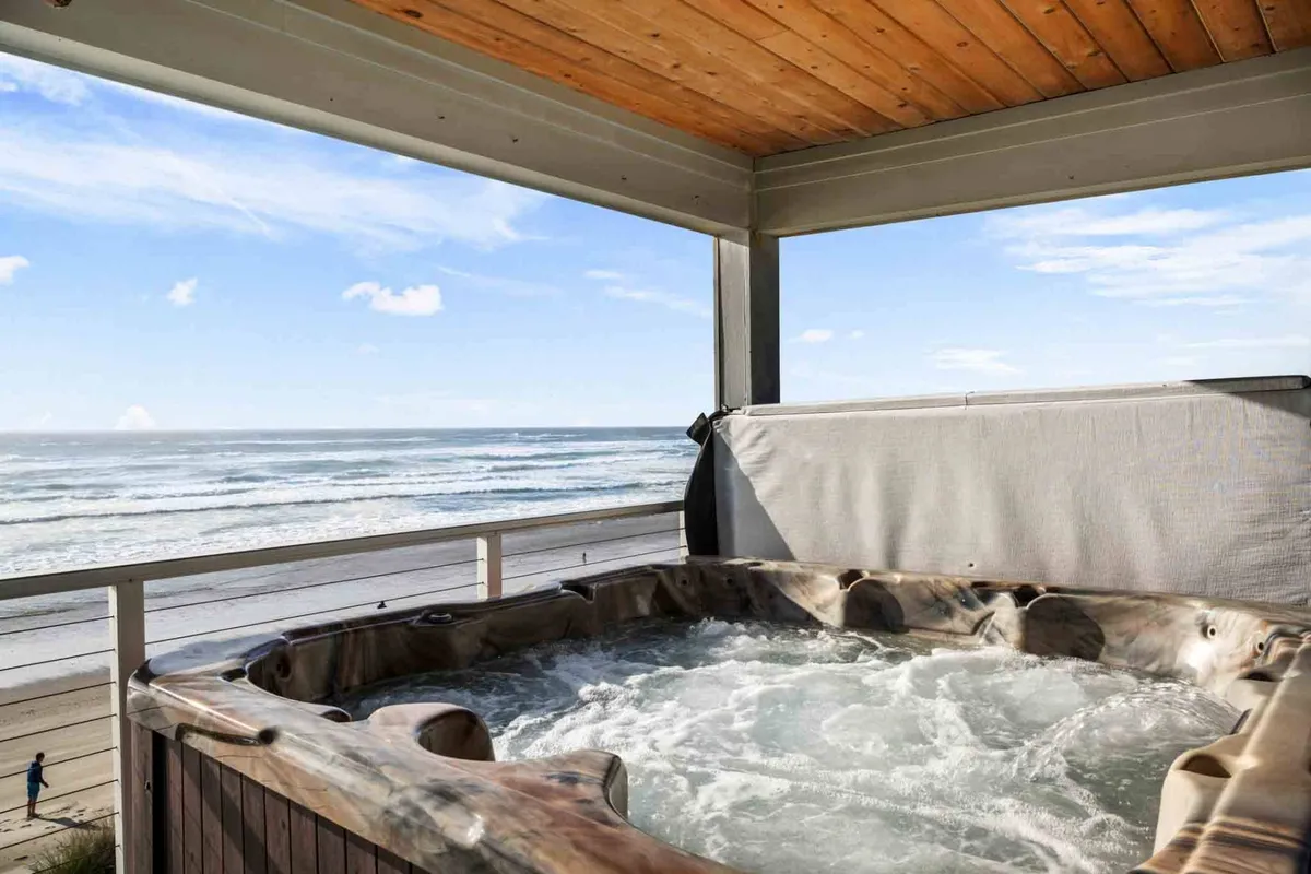 This exterior image features a hot tub set on a deck with clear views of the ocean and sturdy railing. The ambiance is calm and inviting, perfect for unwinding while watching sunsets or sharing memorable moments with loved ones.